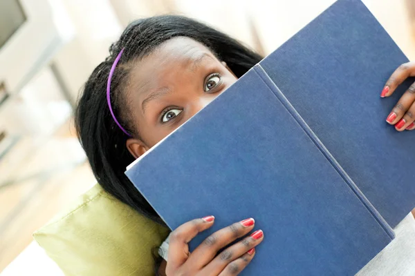 Mulher alegre lendo um livro deitado em um sofá — Fotografia de Stock