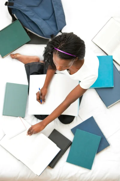 Concentrado adolescente chica estudiando sentado en su cama —  Fotos de Stock