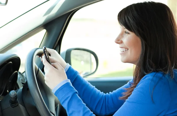 Χαμογελώντας έφηβος κορίτσι χρησιμοποιώντας ένα κινητό τηλέφωνο κατά την οδήγηση — Φωτογραφία Αρχείου
