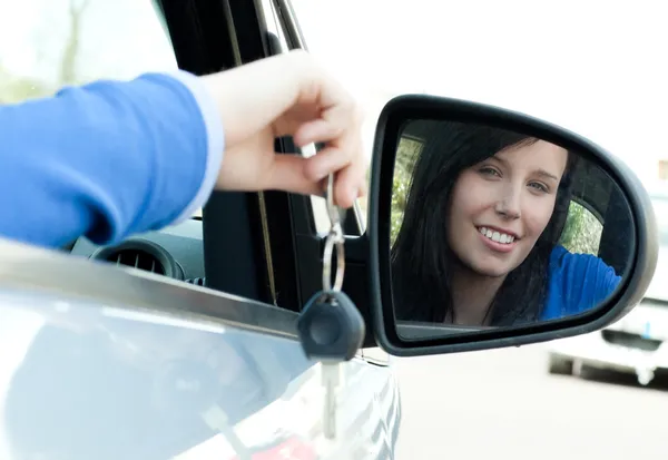 Fröhliches Teenager-Mädchen sitzt in ihrem Auto und hält Schlüssel in der Hand — Stockfoto