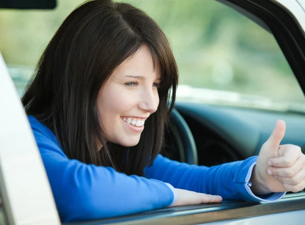 Sonriente adolescente con un pulgar arriba sentado en su coche — Foto de Stock