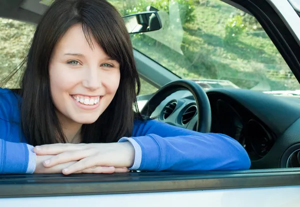 Щаслива дівчина-підліток посміхається на камеру, сидячи в її машині — стокове фото