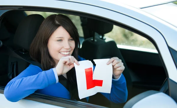 Joyful teen girl sitting in her car tearing a L-sign — Stock Photo, Image