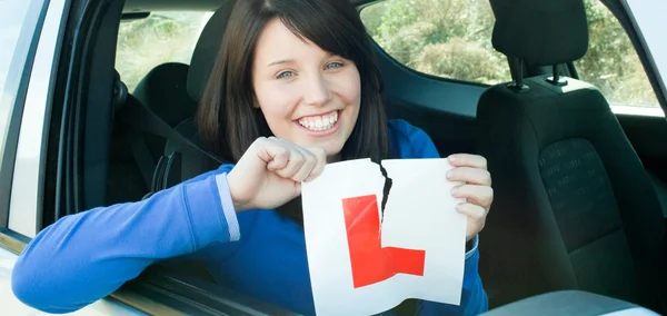 Lächelndes Teenie-Mädchen, das in ihrem Auto sitzt und ein L-Schild zerreißt — Stockfoto