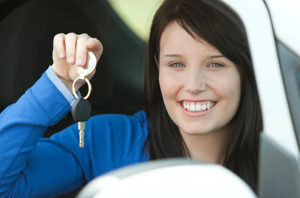 布鲁内特十几岁的女孩坐在她的车持有钥匙 — 图库照片