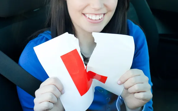 Charming teen girl sitting in her car tearing a L-sign — Stock Photo, Image