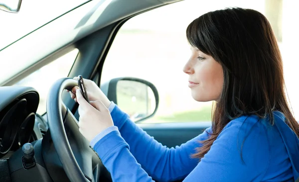 Menina adolescente atraente usando um telefone celular enquanto dirige — Fotografia de Stock