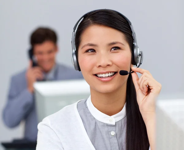 Youg asian businesswoman with headset on at her desk — Stock Photo, Image