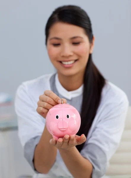 Glimlachende zakenvrouw geld te besparen in een spaarpot — Stockfoto