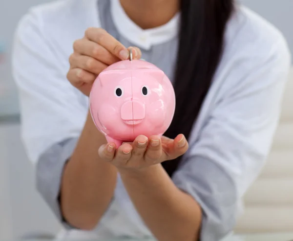 Close-up of a businesswoman saving money in a piggybank — Stok fotoğraf