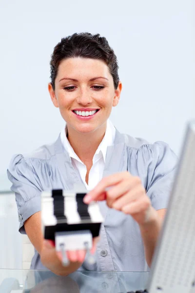 Brunette businesswoman consulting a business card holder — Stock Photo, Image