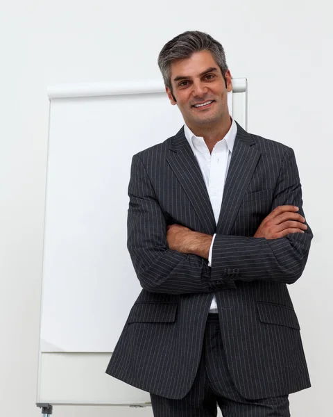 Businessman with folded arms in front of a board — Stock Photo, Image