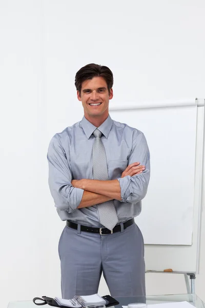 Charming businessman with folded arms in front of a board — Stock Photo, Image