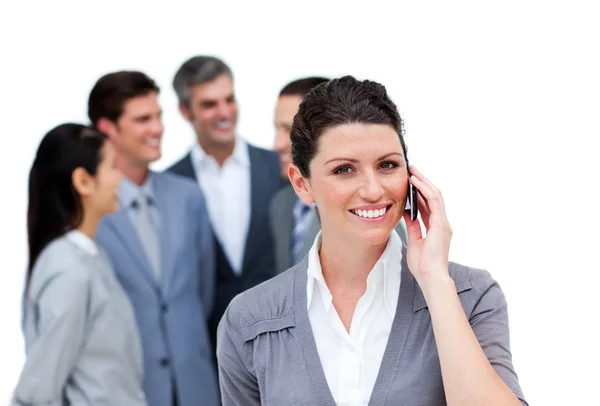 Brunette woman talking on phone in front of her team — Stock Photo, Image