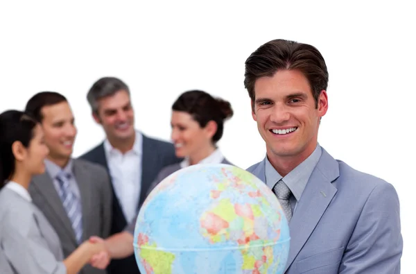 Un homme d'affaires heureux tenant un globe devant son équipe — Photo