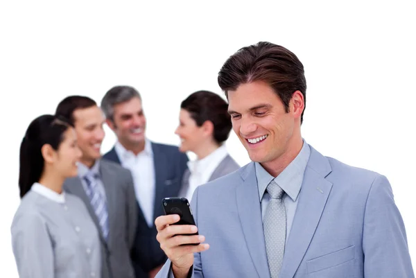 Joven hombre de negocios y su teléfono móvil de pie aparte de su equipo — Foto de Stock