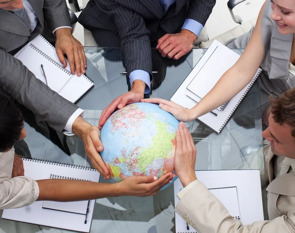 Alto ángulo del equipo empresarial que sostiene un globo terrestre — Foto de Stock