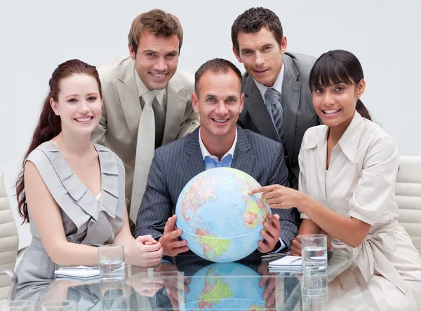 Sonriente equipo de negocios sosteniendo un globo terrestre — Foto de Stock