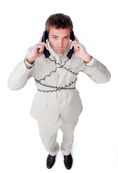 Hombre de negocios cansado enredado en cables de teléfono —  Fotos de Stock
