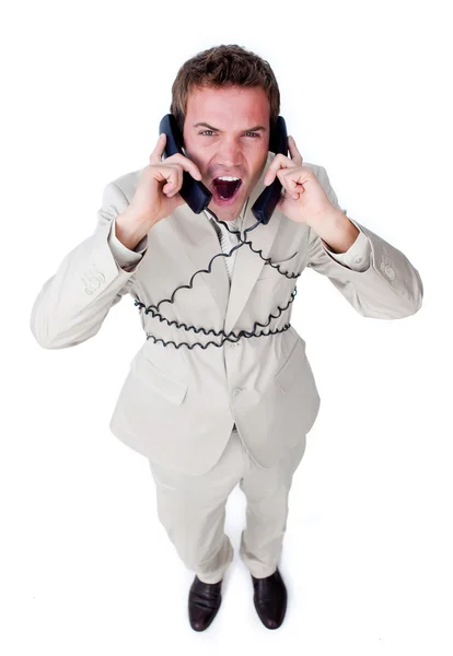 Enojado hombre de negocios enredado en cables de teléfono —  Fotos de Stock