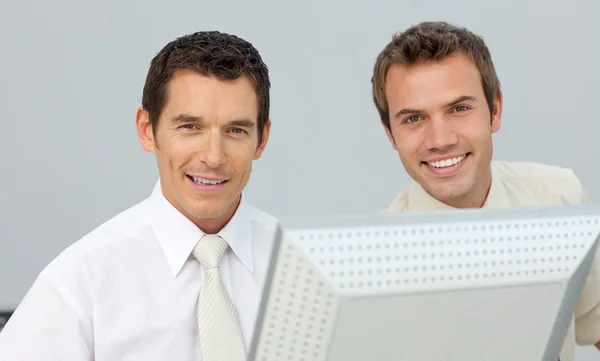 Hombres de negocios sonrientes trabajando juntos en una computadora —  Fotos de Stock