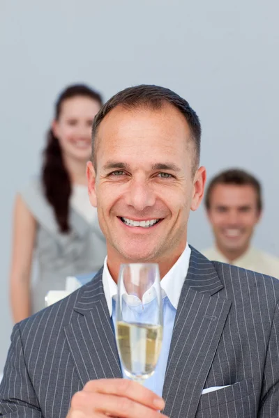 Exitoso hombre de negocios sosteniendo Champagne con su equipo — Foto de Stock