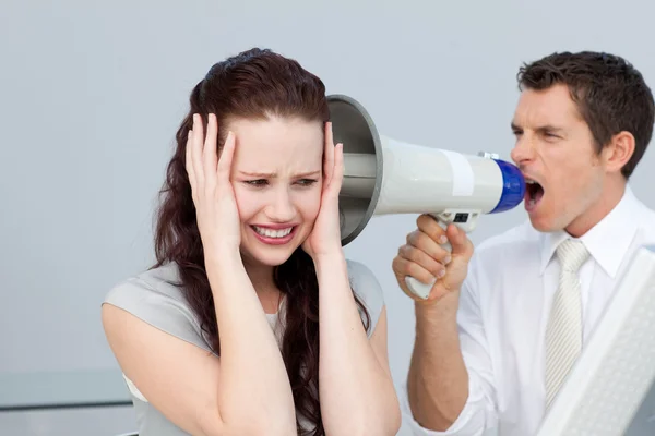 Businessman yelling through a megaphone at a businesswoman — Stock Photo, Image