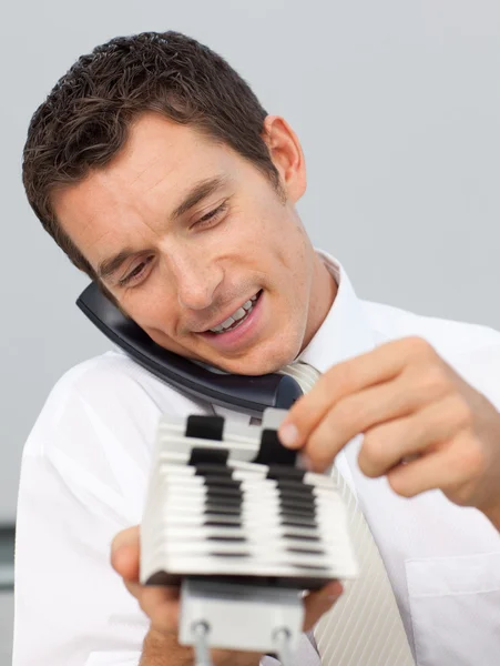 Empresário sorrindo no telefone e consultando um titular do cartão — Fotografia de Stock