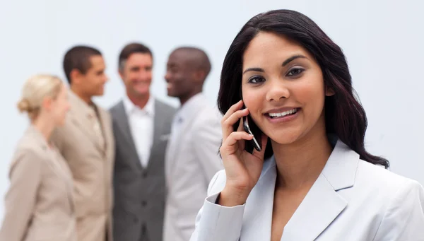 Mulher de negócios étnica ao telefone com sua equipe em segundo plano — Fotografia de Stock