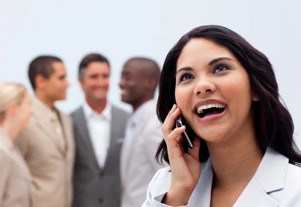 Glad affärskvinna på telefon med sitt team i bakgrunden — Stockfoto