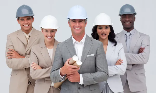Architecturale team glimlachen op de camera met harde hoeden — Stockfoto