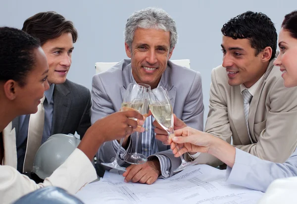 Счастливая команда инженеров празднует успех с шампанским — стоковое фото