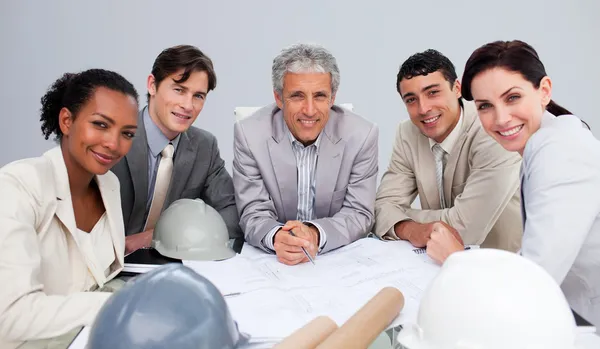 Lächelnde Architekten bei einem Treffen, bei dem sie Pläne studierten — Stockfoto
