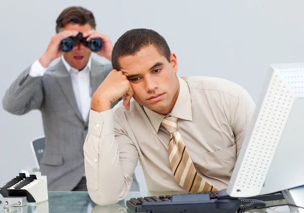 Angry businessman annoyed by a man looking through binoculars — Stock Photo, Image