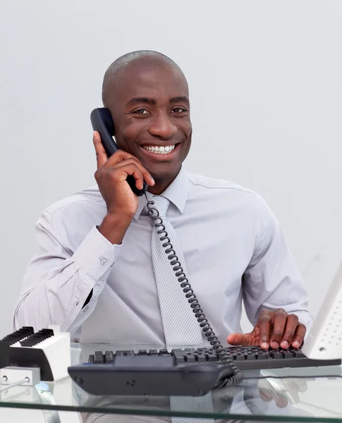 Улыбающийся афро-американский бизнесмен по телефону в офисе — стоковое фото