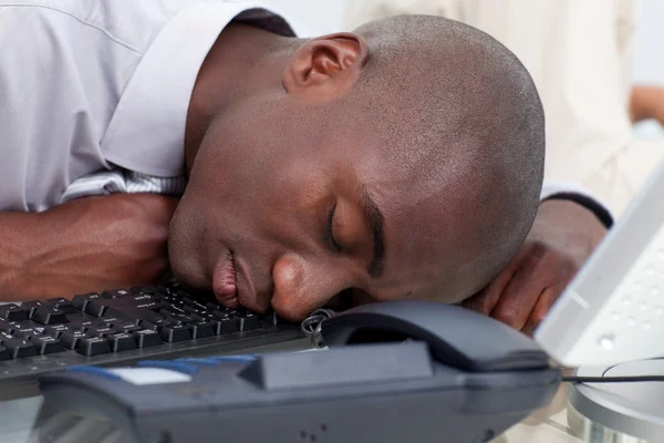 Афроамериканский бизнесмен спит на клавиатуре — стоковое фото