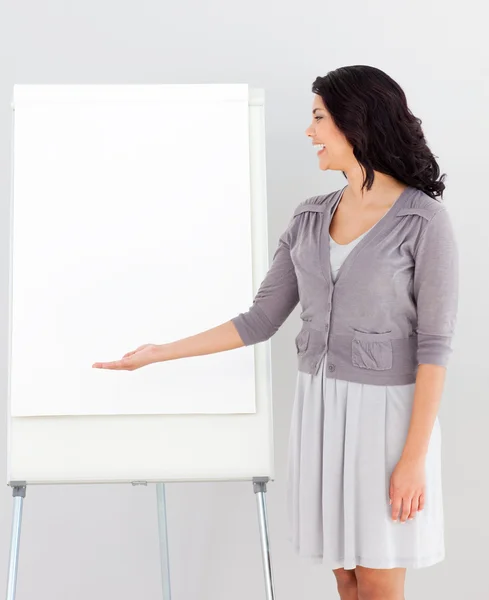 Affärskvinna ler och pekar på presentation styrelse — Stockfoto