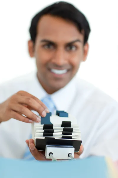 Smiling businessman consulting a business card holder — Stock Photo, Image