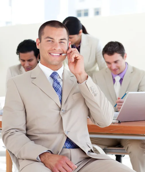 Smiling manager with headset on in front of his team — Stock Photo, Image