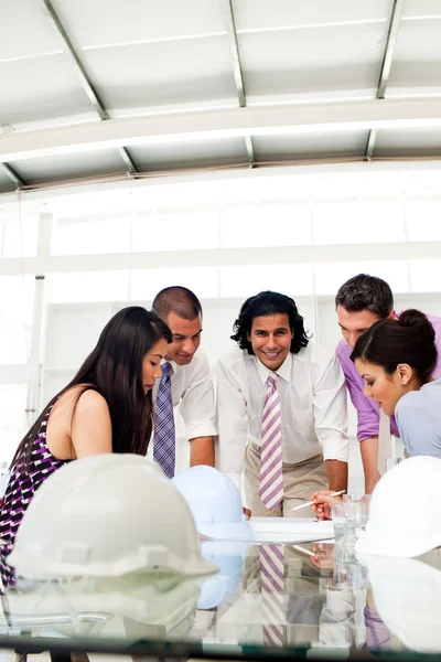 Multi-thnic engineer co-workers reviewing blueprints — Stock Photo, Image