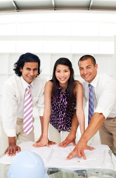 Multi-ethnic architect co-workers reviewing blueprints — Stock Photo, Image