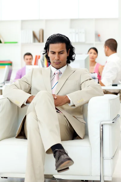 Sério gerente sentado em uma poltrona na frente de sua equipe — Fotografia de Stock