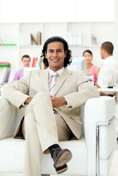 Confident manager sitting in an armchair in front of his team — Stock Photo, Image