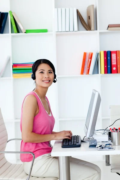 Glimlachende zakenvrouw met headset op in het kantoor — Stockfoto