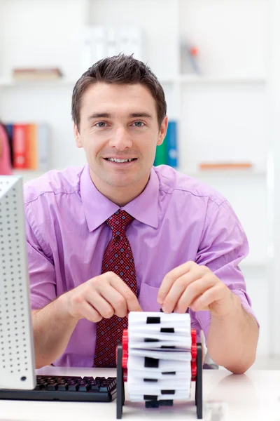 Hombre de negocios sonriente consultando al titular de su tarjeta de visita — Foto de Stock