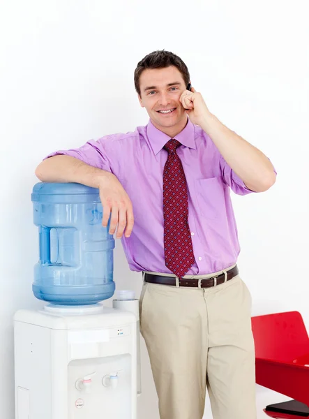Empresario en el teléfono por el refrigerador de agua —  Fotos de Stock