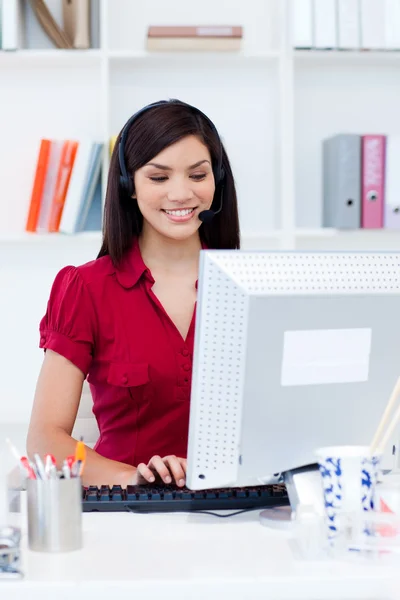 Mujer de negocios sonriente con auriculares en una computadora —  Fotos de Stock