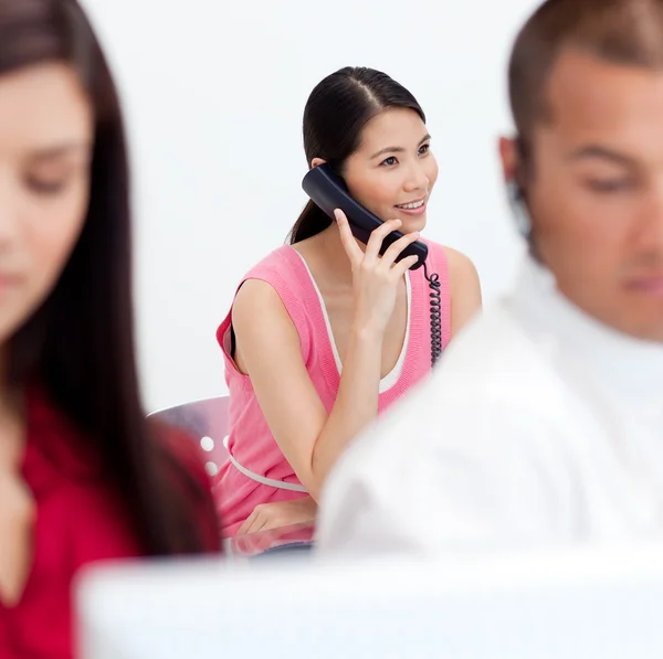 stock image Asian businesswoman on phone with her colleagues in the foregrou