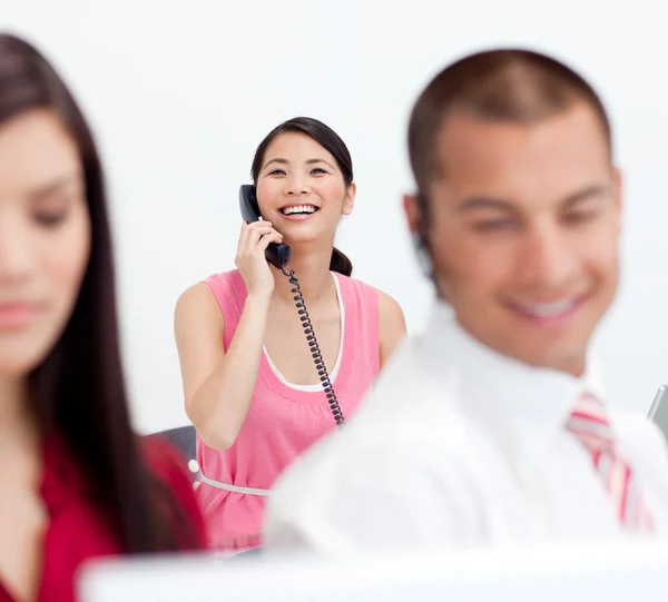 Leende affärskvinna på telefon med sina kollegor i händer — Stockfoto