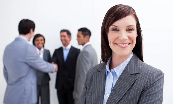 Smiling female executive with her team in the background — Stock Photo, Image